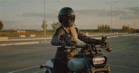Blonde Woman Dressed In Black Helmet Mask Leather Jacket Sitting On