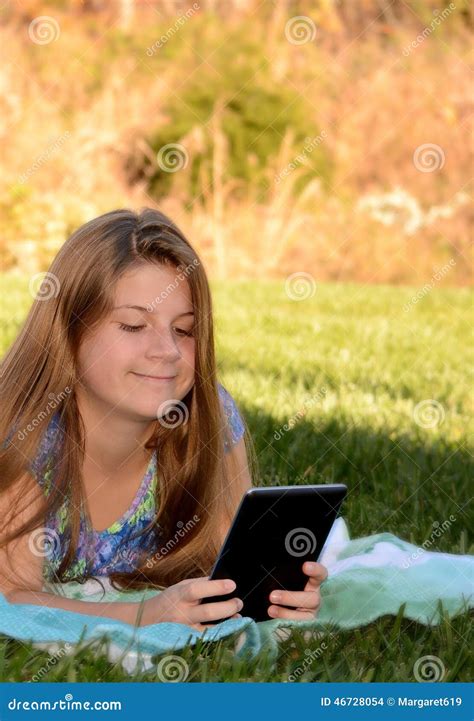 Une Petite Fille Se Trouvant Sur L Herbe Avec Son Comprim Photo Stock