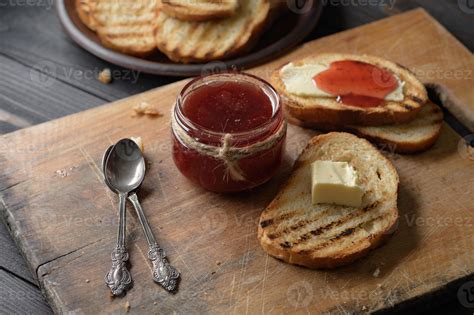 pan tostado con mermelada de fresa casera y sobre mesa rústica con