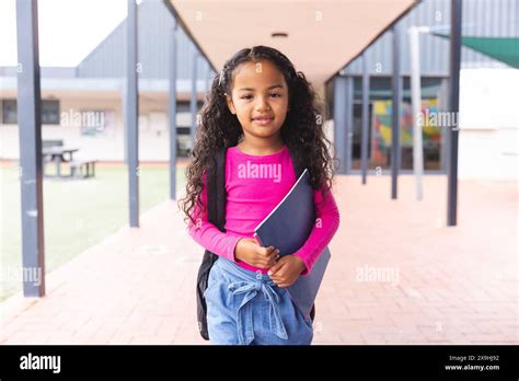 In School Young Biracial Girl Holding A Book Standing Outside