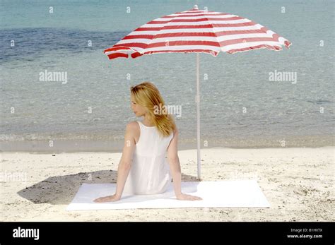 Femme blonde assise sur une plage de sable Banque de photographies et dimages à haute