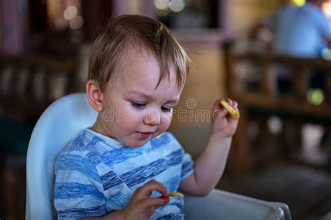 Un Chico Lindo Comiendo Papas Con Los Dedos Foto De Archivo Imagen De