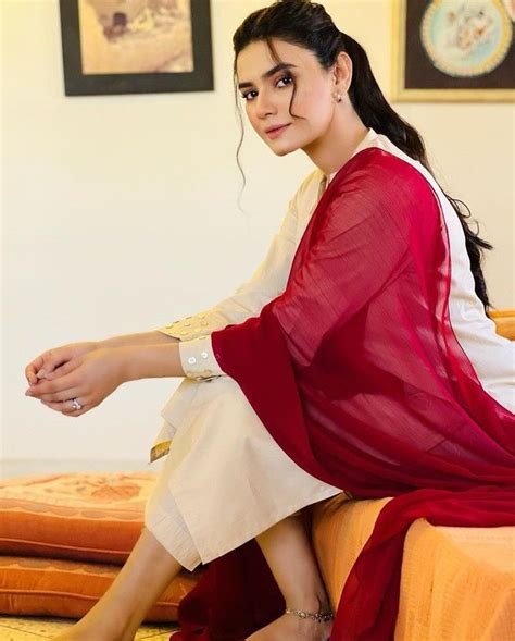 A Woman Sitting On Top Of A Bed Wearing A Red And White Dress With