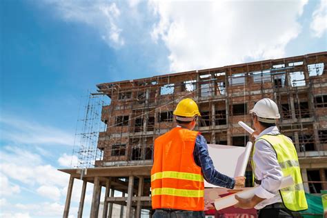 Empresario E Ingeniero Mirando Un Plano De Construcción En Un Sitio De