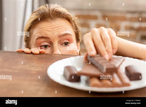 Dark Eyed Mature Woman With Allergy Taking Piece Of Chocolate Stock