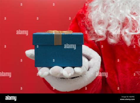Santa Claus Handing A Christmas T Box Over Red Background Stock