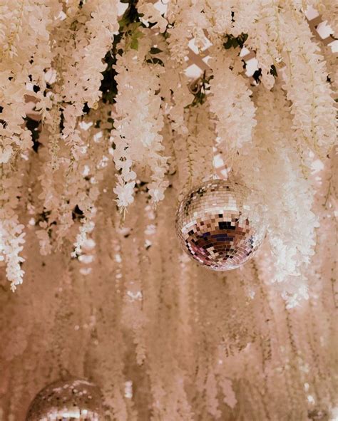 Disco Ball Hanging From The Ceiling In Front Of White Flowers