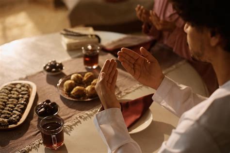 Close Up Of Muslim Man And His Wife Praying Together At Dining Table