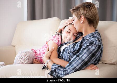 Belle mère embrasse sa fille adolescente sur le canapé Photo Stock Alamy