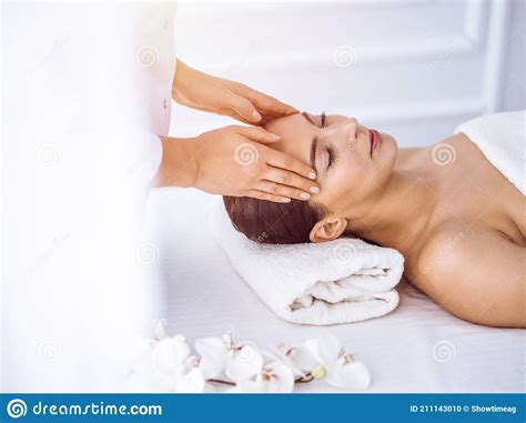 Beautiful Brunette Woman Enjoying Facial Massage With Closed Eyes In