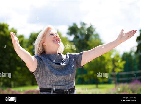 Happy Elderly Blonde Woman In Blue Dress On The Background Of Summer