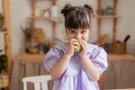 Una Ni A Encantadora Con Un Vestido Lila Come Una Manzana Verde En La