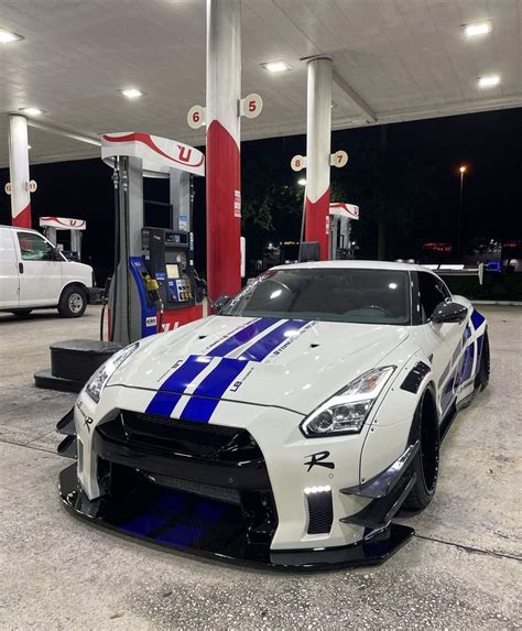 A White And Blue Sports Car Parked At A Gas Station