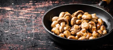 Champiñones pequeños fritos en una sartén Foto Premium