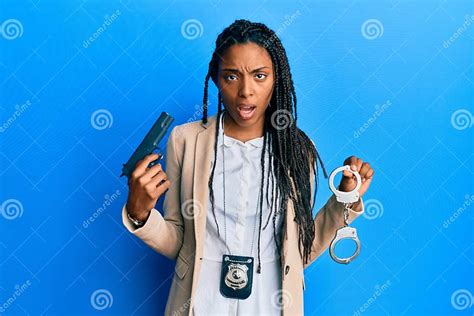 African American Police Woman Holding Gun And Handcuffs Clueless And