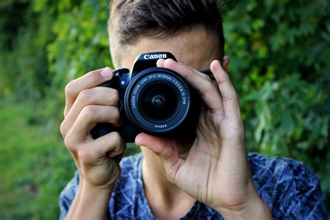 Man In Blue Shirt Holding Black Canon Camera Free Image Peakpx