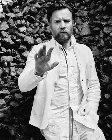 A Man In A White Suit And Tie Making The Vulcan Sign With His Hands