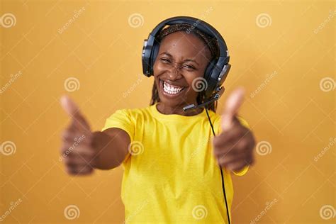 African American Woman Listening To Music Using Headphones Approving