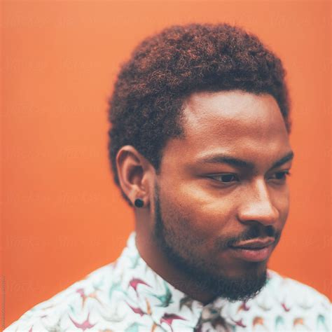 Square Portrait Of Modern Young Black Man In Front A Orange Wall By