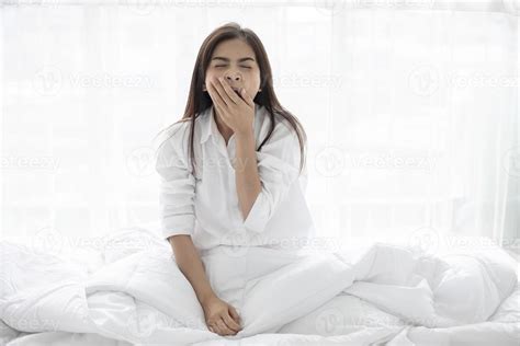 Asian Woman Beautiful Young Smiling Woman Sitting On Bed And Stretching In The Morning At