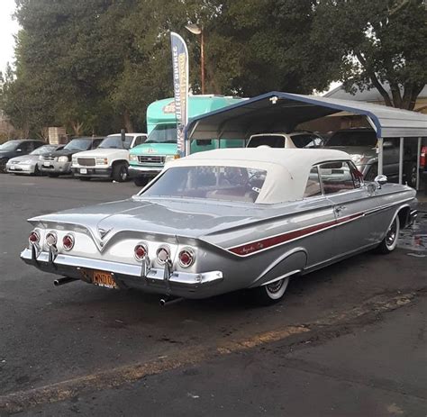 An Old Car Is Parked In Front Of A Gas Station On The Side Of The Road