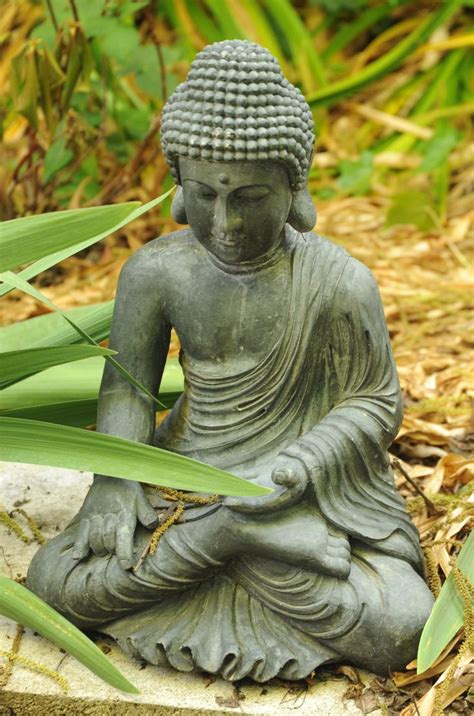 Statue Of Lord Buddha Seated In A Garden Wearing Robes Earth Touching