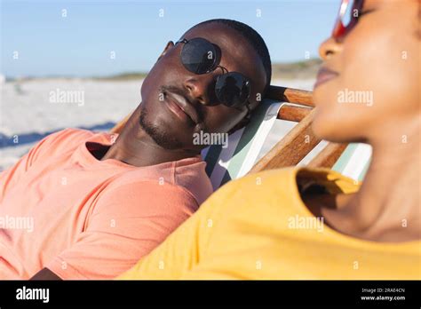 Happy African American Couple In Sunglasses Sitting In Deckchairs