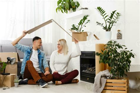 Young Couple Carrying Big Cardboard Box At New Home Moving House