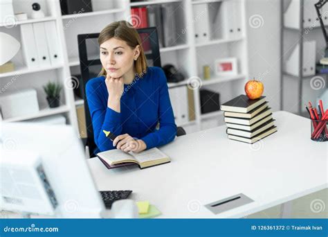 A Young Girl Sits At A Computer Desk And Holds A Yellow Marker In Her