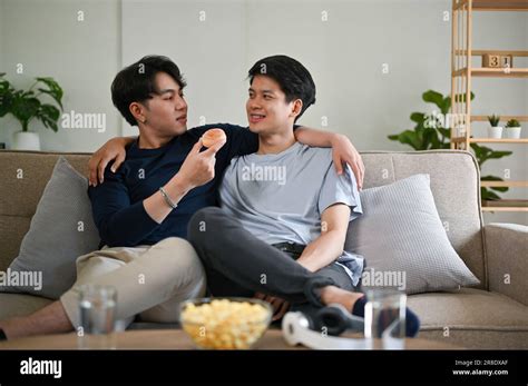 A Handsome And Happy Young Asian Gay Man Feeds A Doughnut To His Boyfriend While Relaxing On A