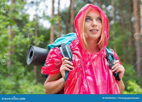 Beautiful Backpacker In Raincoat Looking Away At Forest Stock Photo