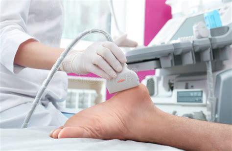 Doctor Conducting Ultrasound Examination Of Patient`s Foot In Clinic