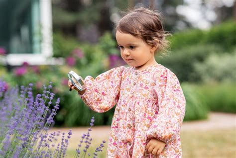 Petite Fille Avec Loupe Regardant Les Fleurs Du Jardin Photo Stock