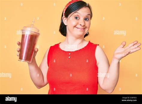 Brunette Woman With Down Syndrome Holding Glass Of Smoothie Celebrating