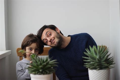 Retrato De Padre E Hijo Sentados Con Plantas De Interior En Casa Foto