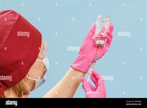 Female Physician In A Medical Uniform Holding A Glass Bottle And