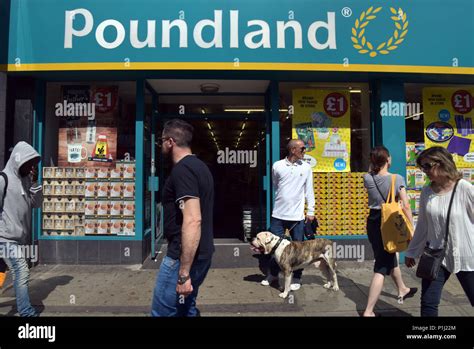 People And Shoppers Walk Past The Discount Store Poundland On Camden