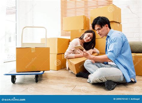 Happy Asian Couple Moving To A New House Woman Unboxing Cardboard