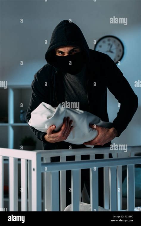 Kidnapper in black clothes and mask holding infant child Stock Photo ...