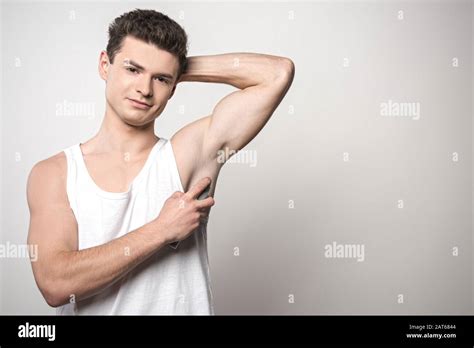 Handsome Man In White Sleeveless Shirt Applying Deodorant On Underarm