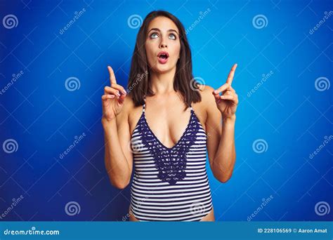 Beautiful Woman Wearing Bikini Swimwear Over Blue Isolated Background Amazed And Surprised