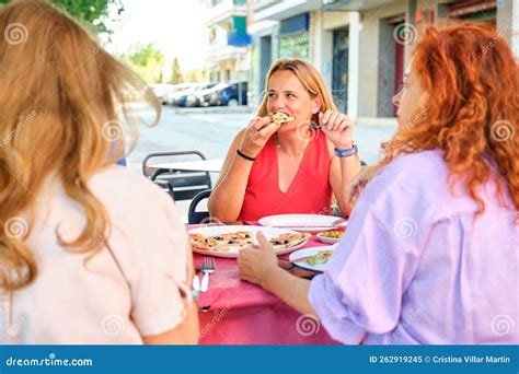 Mature Woman Eating Pizza With Friends At A Restaurant Stock Image