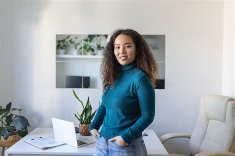 Souriante jeune employée asiatique se tenir au bureau dans le bureau