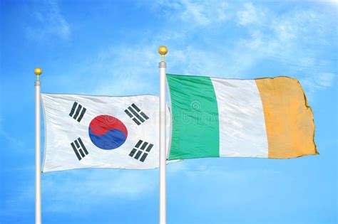 South Korea And Ireland Two Flags On Flagpoles And Blue Cloudy Sky