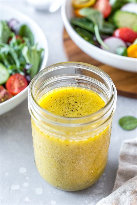 An Easy Dijon Vinaigrette Recipe In A Mason Jar Next To A Bowl Of Salad