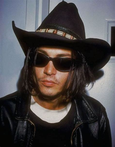 A Man With Long Hair Wearing A Black Hat And Sunglasses On His Head Is