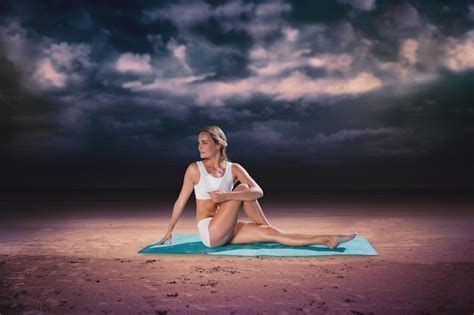 Premium Photo Gorgeous Fit Blonde In Seated Yoga Pose Against Dark Cloudy Sky