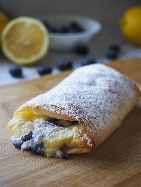 A Pastry With Blueberries And Powdered Sugar On It Sitting On A Cutting