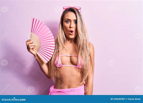 Joven Hermosa Mujer Con Bikini Y Gafas De Sol Usando Un Ventilador De Mano Sobre Fondo Rosado