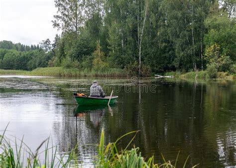 A Fisherman In A Boat Calm Lake Water Surface Tree Reflections